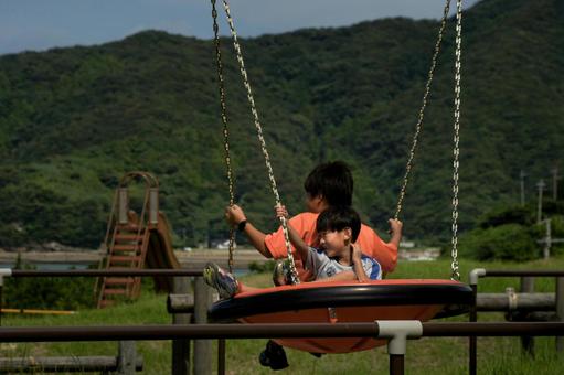 <素材>新緑の公園でブランコで遊ぶ子供 <素材>新緑の公園でブランコで遊ぶ子供の写真