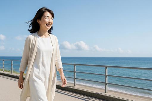 海辺を歩く中年女性 海辺を歩く中年女性の写真