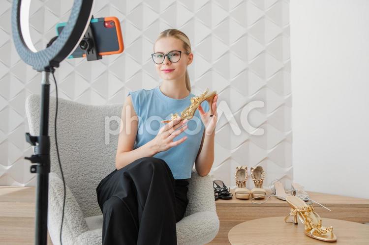 サンダルを持ち座るメガネ女性 女性,サンダル,持つの写真素材