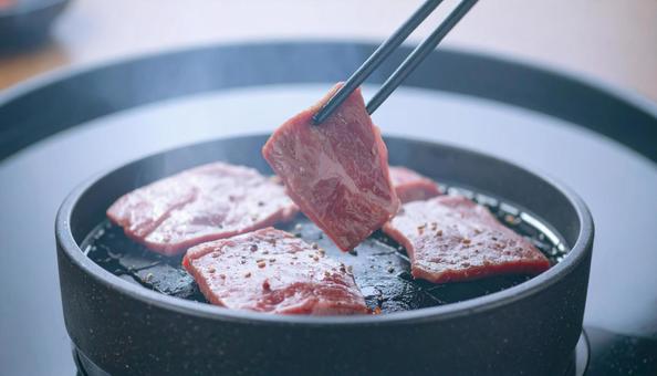 焼肉を鉄板で焼いて鉄箸ですくう 焼肉を鉄板で焼いて鉄箸ですくうの写真