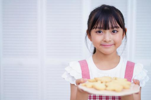 クッキーが盛られたお皿を見せる女の子のポートレート 女の子,クッキー,持つの写真素材