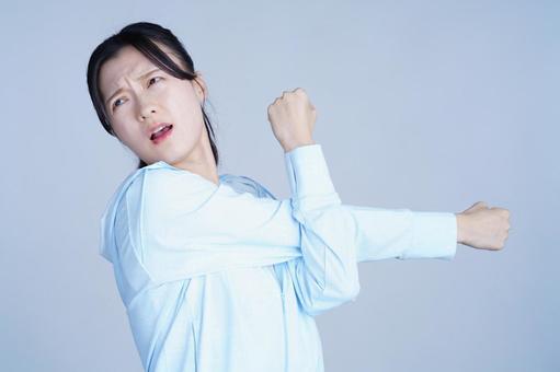 水色の服の女性が腕を曲げて力こぶを見せる 女性,腕を伸ばす,ストレッチの写真素材