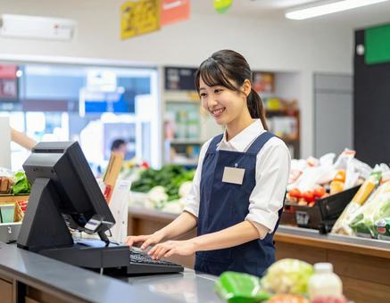 スーパーで笑顔でレジ業務をする女性店員 スーパーで笑顔でレジ業務をする女性店員の写真