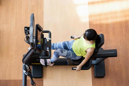 ジムでトレーニングする若い女性 ジム,エアロバイク,フィットネスバイクの写真素材