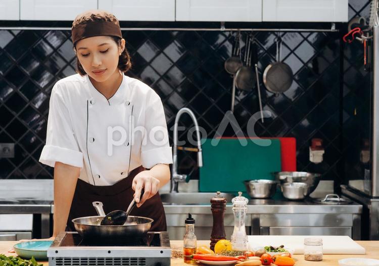 フライパンで調理スプーンで炒める女性シェフ キュイジーヌ,キッチン,厨房の写真素材