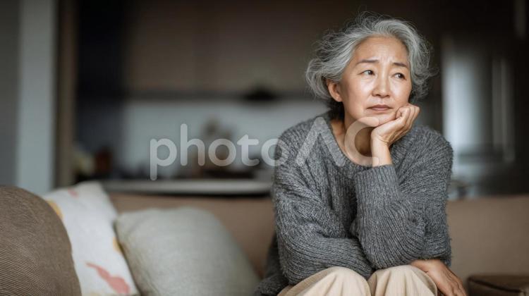 ソファに座り頬杖をつくシニアの女性 女性,シニア,悩みの写真素材
