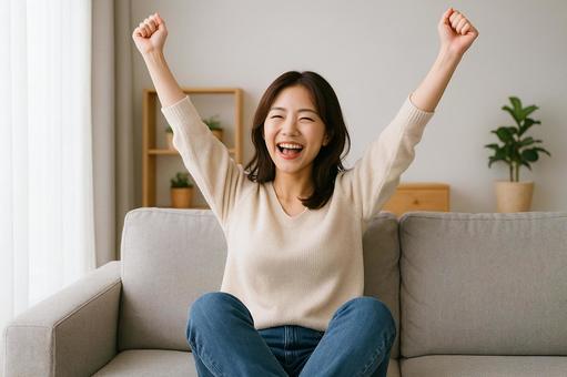 ソファで喜ぶ女性 ソファで喜ぶ女性の写真
