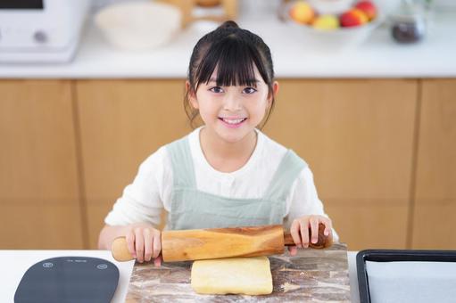 めん棒でクッキー生地を伸ばす笑顔の女の子 女の子,めん棒,持つの写真素材