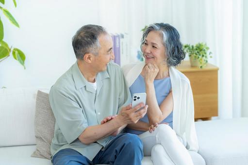 リビングでスマホを見るシニア夫婦 リビングでスマホを見るシニア夫婦 スマホ,シニア,笑顔の写真素材