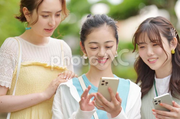 公園でスマートフォンを見ている3人の女性 女子旅,女性,日本人の写真素材