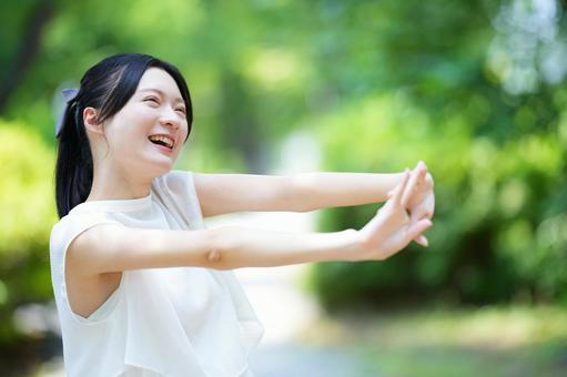 白いノースリーブワンピースの女性が笑顔で手を差し出す 女性,笑顔,腕を伸ばすの写真素材