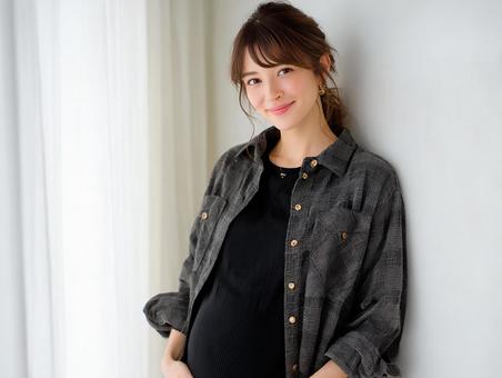 室内でお腹に手を添えて微笑む妊婦さん 室内でお腹に手を添えて微笑む妊婦さんの写真