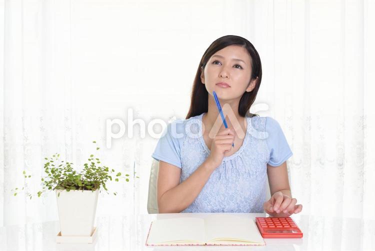 ノートと電卓を使う女性 女性,笑顔,ノートの写真素材