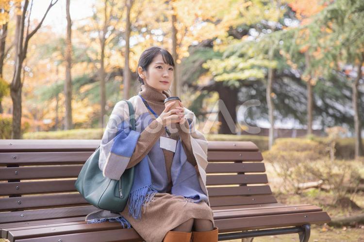 秋の公園でコーヒーを飲む会社員の女性（寒い） 寒い,コーヒー,秋の写真素材