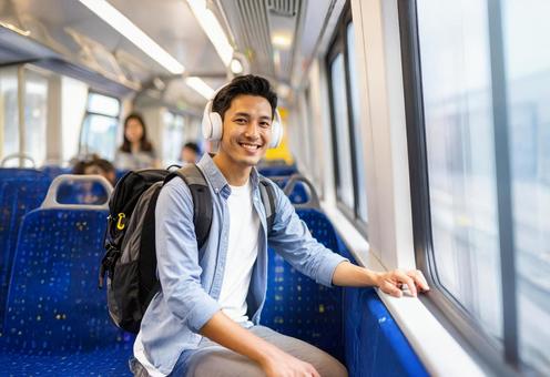 ヘッドフォンをつけて電車に乗る男性 ヘッドフォンをつけて電車に乗る男性の写真