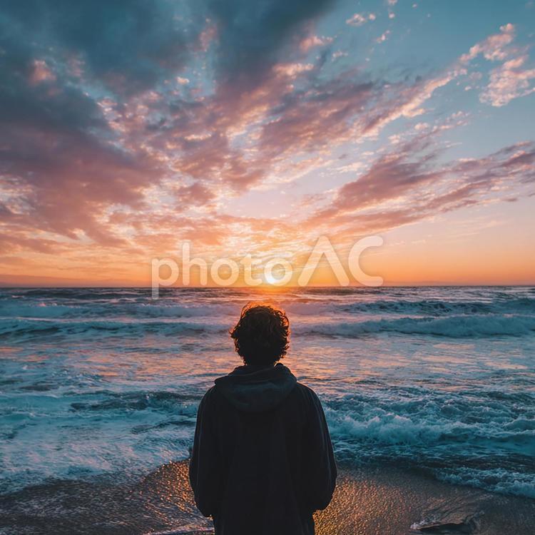 穏やかな波打ち際で夕焼けを見つめる人物 男性,後ろ姿,海の写真素材
