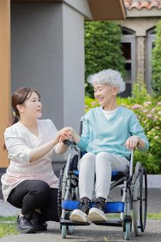 庭で車椅子に乗るシニア女性とヘルパー 庭で車椅子に乗るシニア女性とヘルパー シニア,車椅子,散歩の写真素材