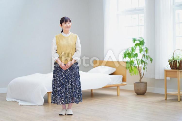 明るい寝室に立つ笑顔の中年女性 家政婦,主婦,シニアの写真素材