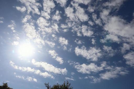 白い太陽と雲と青空の秋の空の写真