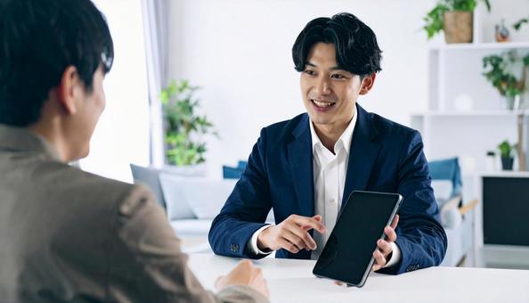 タブレットを使って説明する男性営業マン タブレットを使って説明する男性営業マンの写真