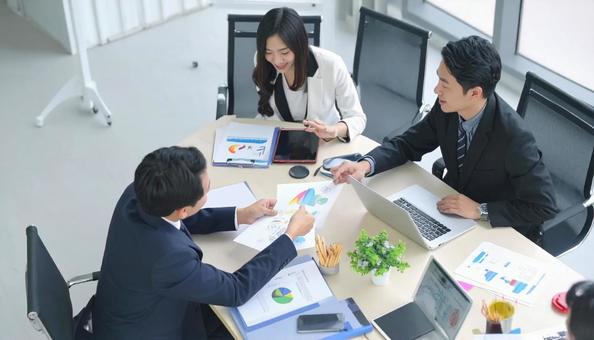テーブルを囲んで会議するビジネスパーソンの写真