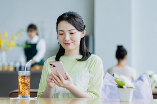 カフェでスマホを使う若い女性 カフェでスマホを使う若い女性 女性,カフェ,笑顔の写真素材