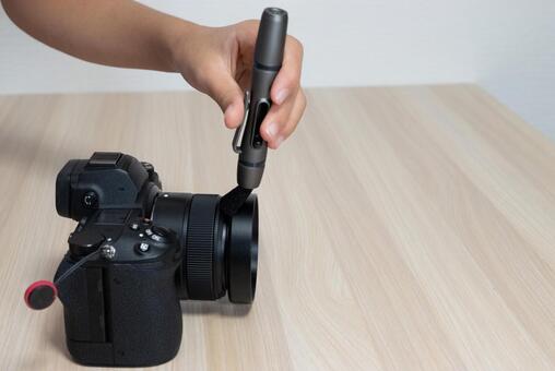 レンズペンでカメラのレンズを清掃する手元 カメラ,ミラーレス一眼,レンズペンの写真素材