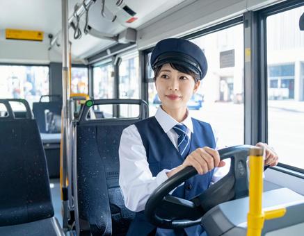 運転席で前方を見つめる女性バス運転手 運転席で前方を見つめる女性バス運転手の写真
