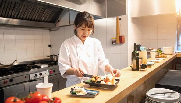 レストランの調理場で料理するスタッフ女性 レストランの調理場で料理するスタッフ女性の写真