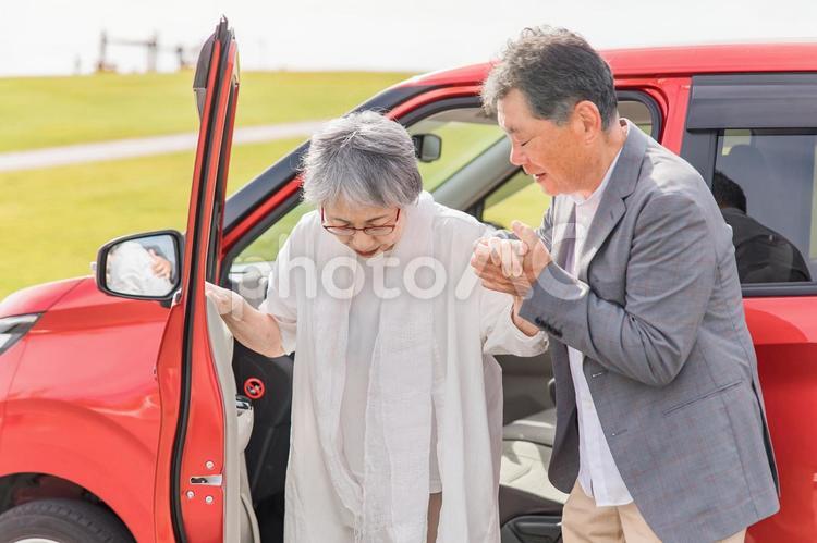 自動車から降りる高齢者女性と介助する男性 介護,高齢者,自動車の写真素材