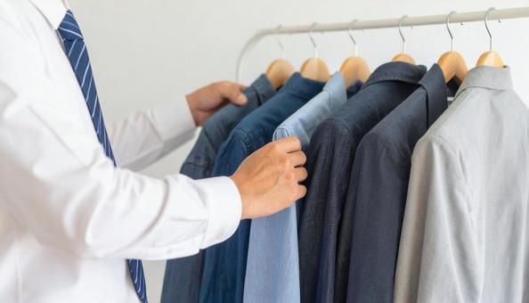 ハンガーにかかる私服を取るビジネスマン ハンガーにかかる私服を取るビジネスマンの写真