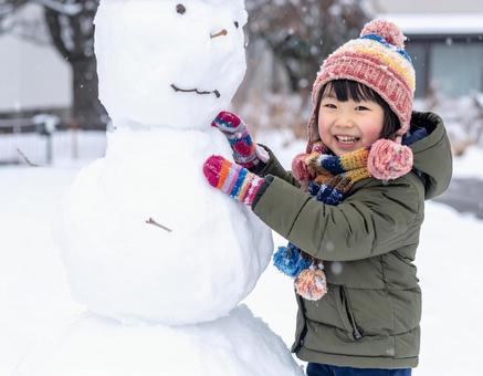 雪だるまを作って喜ぶ子供の冬の屋外風景 雪だるまを作って喜ぶ子供の冬の屋外風景の写真