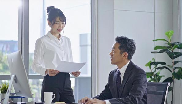 上司に報告する女性社員 上司に報告する女性社員の写真