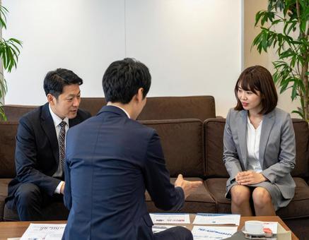 応接室でお客様に資料を説明する上司と部下の写真