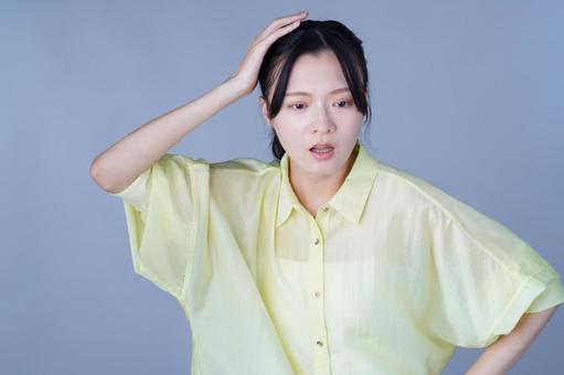 頭をかく黄色い服の女性 女性,困る,真顔の写真素材