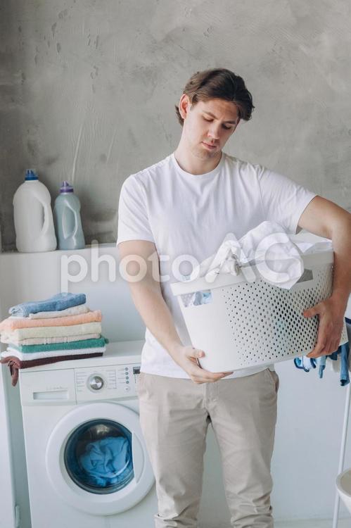 洗濯物を持ってうなだれる男性 男性,人物,洗濯物の写真素材