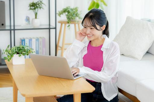 自宅でノートパソコンを操作する若い女性 若い女性,ノートパソコン,笑顔の写真素材