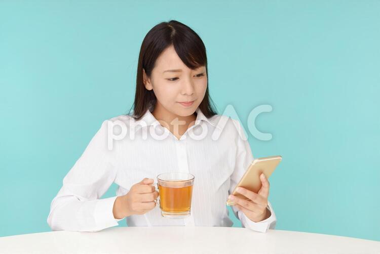 スマートフォンを持つ笑顔の女性 女性,女,紅茶の写真素材