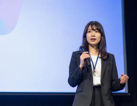 スクリーンの前でプレゼンする女性 スクリーンの前でプレゼンする女性の写真