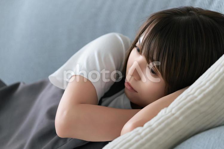 ソファに寝転んで考えごとをする女性 女性,ソファ,考えるの写真素材