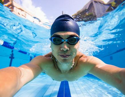 屋外プールで泳ぐ男性の写真