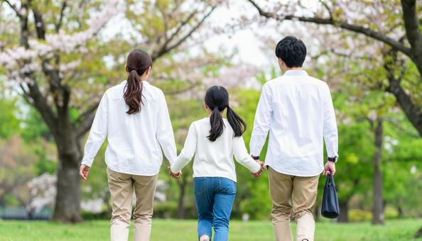 散歩しながら話す3人家族の後ろ姿 散歩しながら話す3人家族の後ろ姿の写真