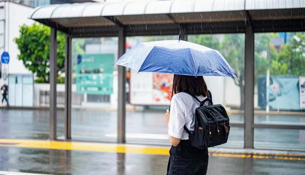 雨の中バス停でバスを待つ日本人女性 雨の中バス停でバスを待つ日本人女性の写真