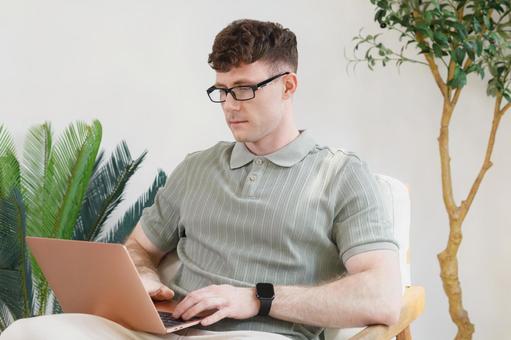 椅子に座って膝の上でノートパソコンを使う男性 男性,外国人,欧米人の写真素材