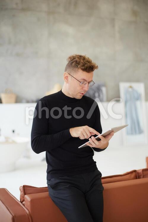 ソファーにもたれてタブレットを使う男性 ビジネス,男性,外国人の写真素材