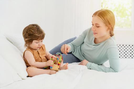 玩具で遊ぶ赤ちゃんを見つめる母 玩具で遊ぶ赤ちゃんを見つめる母 親子,母子,赤ちゃんの写真素材