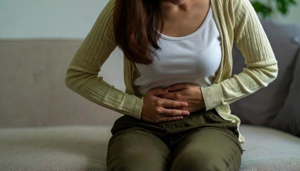 お腹の調子が悪くてお腹をさする若い女性 お腹の調子が悪くてお腹をさする若い女性の写真