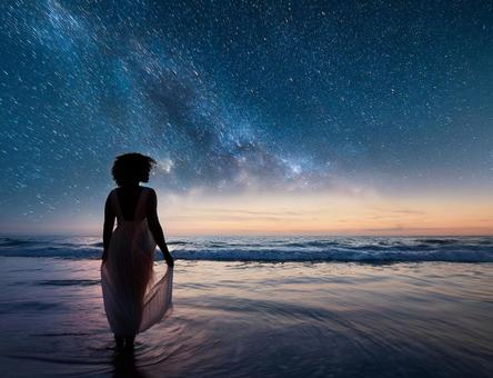 星空と海と女性のシルエットの写真