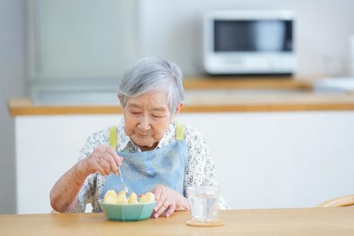フォークでリンゴを刺そうとしている高齢女性 女性,リンゴ,フルーツの写真素材