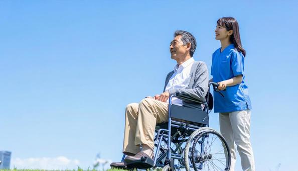 青空を見つめる車いすシニアと介護の女性 青空を見つめる車いすシニアと介護の女性の写真